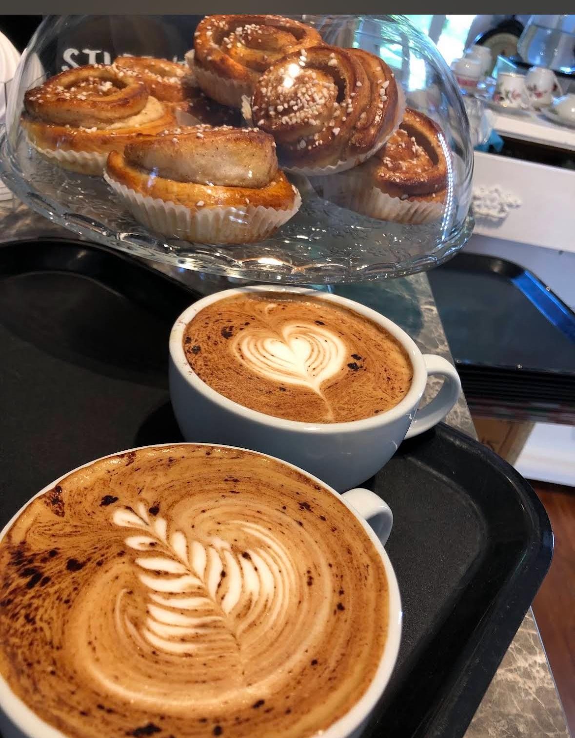 Två koppar kaffe med bakverk bakom glas